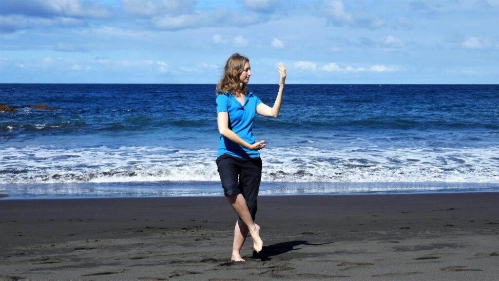 Eine Frau macht Qi Gong-Übungen am Strand